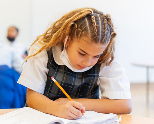 Student writing on paper in class
