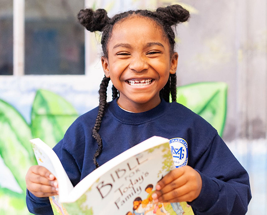 Student happily smiling while reading a book