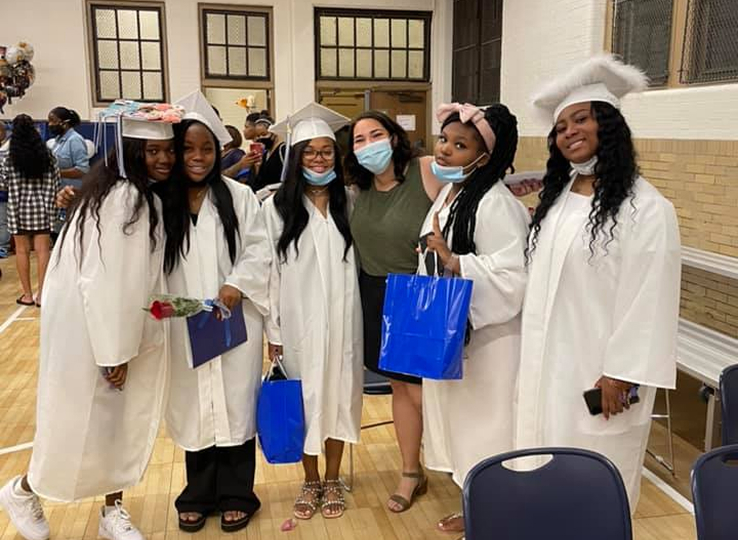Graduating students posing for a picture with faculty inside St Malachy gymnasium
