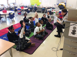 Teacher and students raising their hands at St Malachy Catholic School classroom 