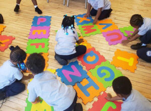 St Malachy students placing alphabet puzzle mats together