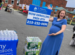 Pregnant woman standing infront of Enrollment Sign