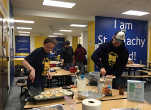 Faculty and volunteers cooking pancakes at St Malachy